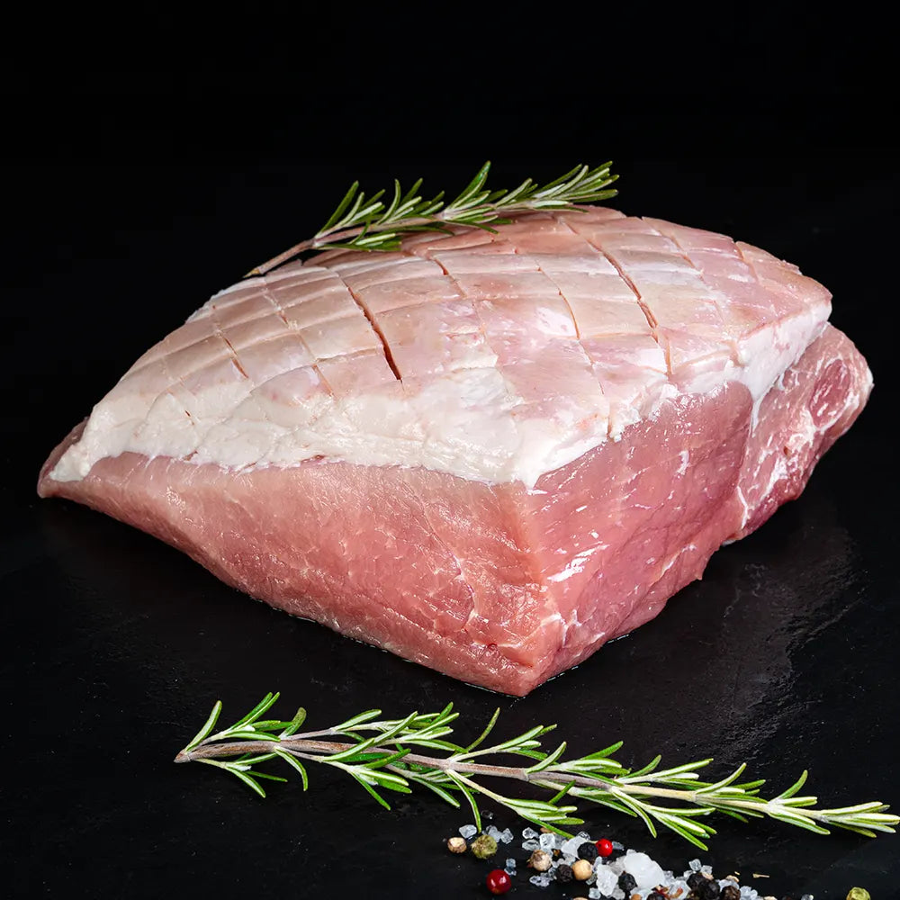 Krustenbraten vom Duroc Strohschwein von der Seite vor dunklem Hintergrund.