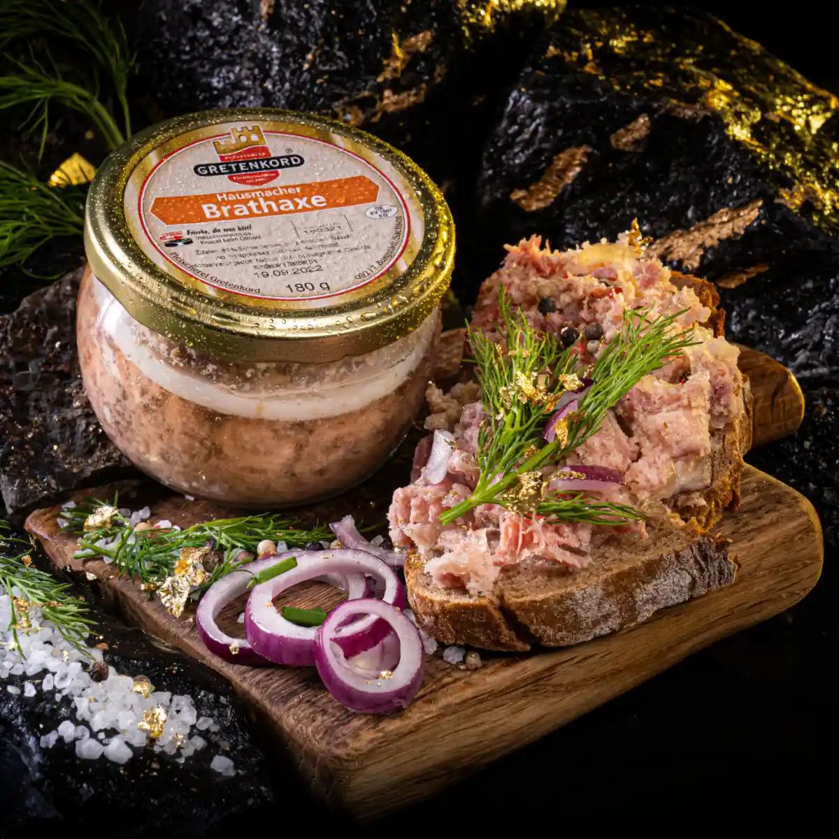 Ein Glas hausmacher Brathaxe und daneben eine Scheibe Brot die damit bestrichen ist