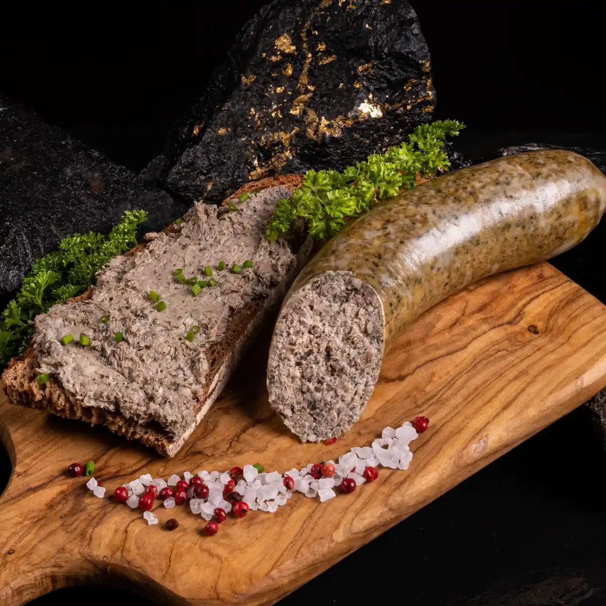 Ein angeschnittenes Stück geräucherte Leberwurst neben einer Brotscheibe mit aufgestrichener Leberwurst