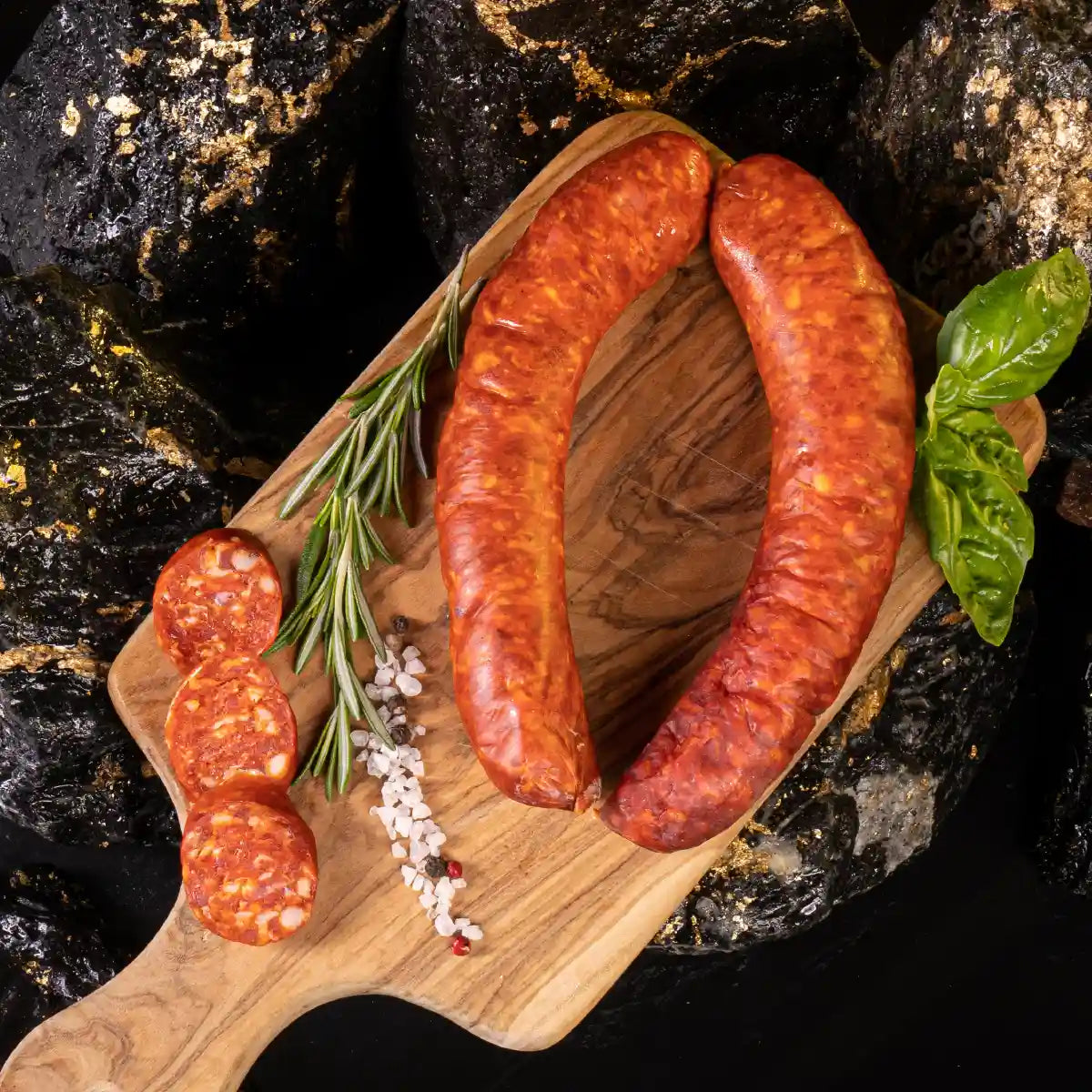 Ein paar Paprikaknacker am Stück und daneben aufgeschnitten einige Scheiben auf hellem Holzbrett