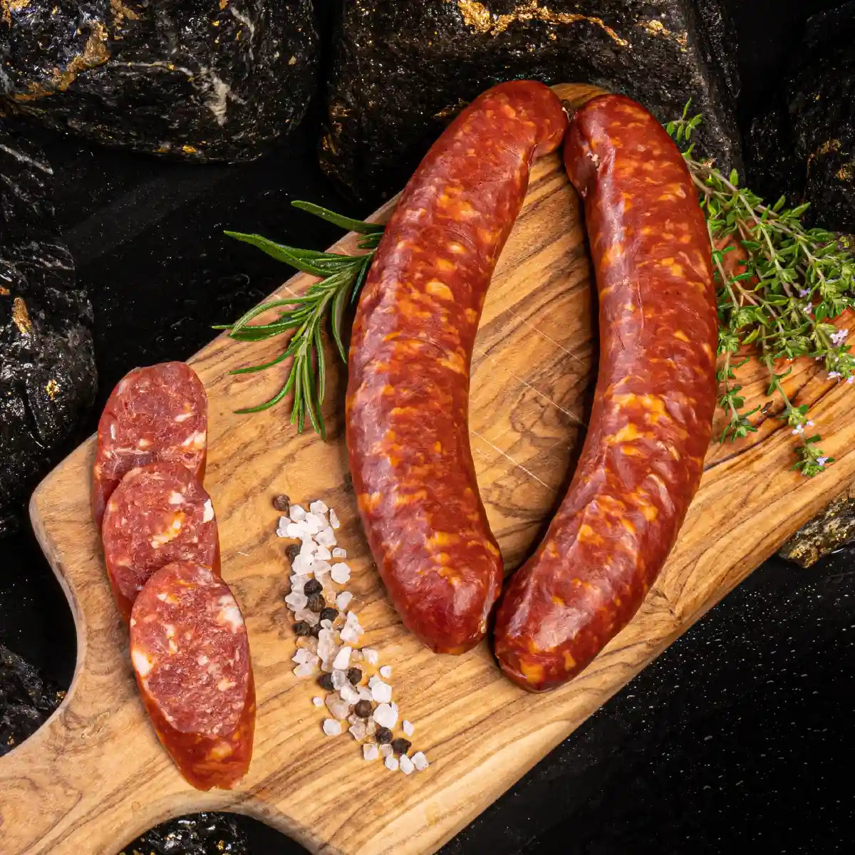 Zwei Stück Schinkenpolnische auf hellem Holzbrett mit aufgeschnittenen Stücken