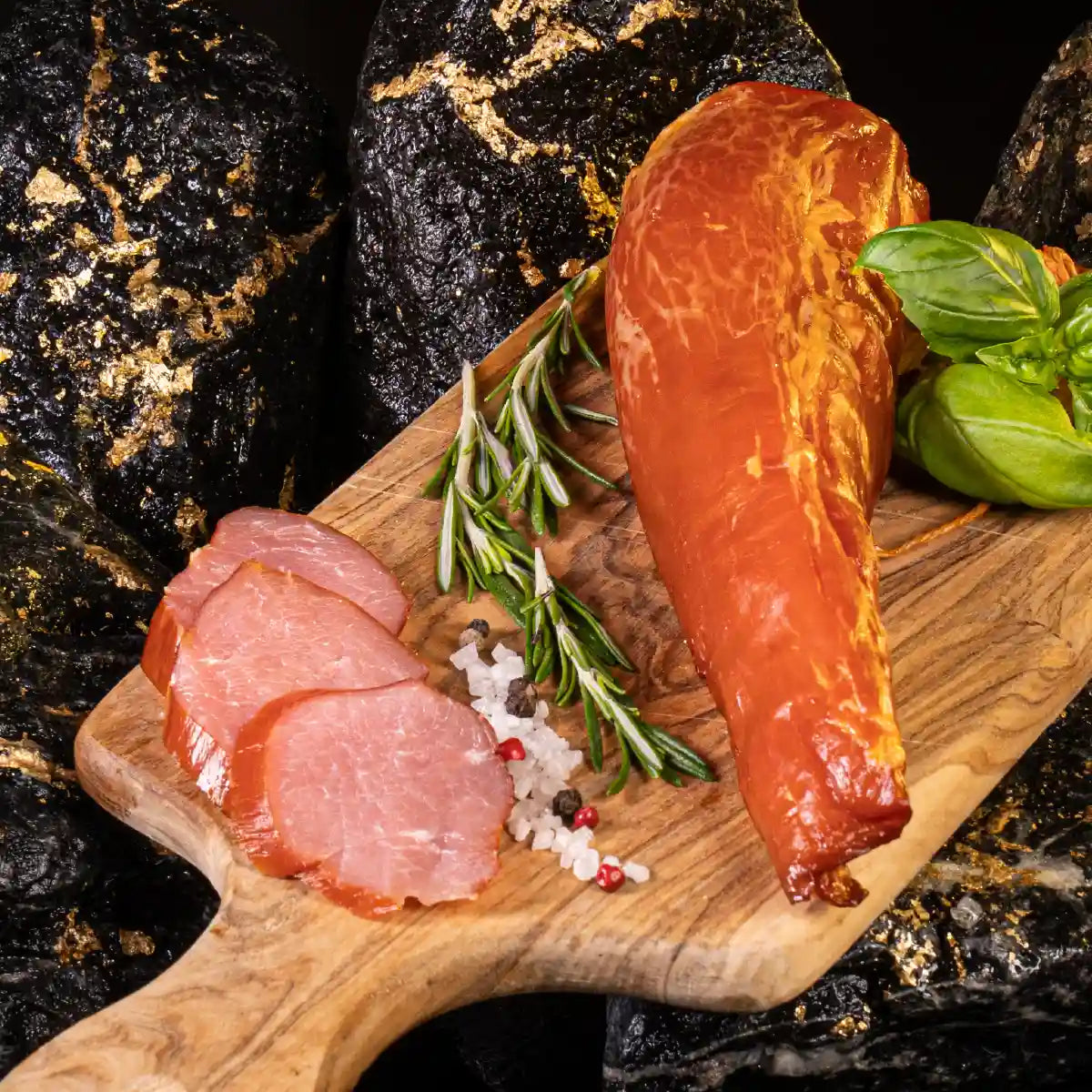 Schweinefilet am Stück auf hellem Holzbrett mit aufgeschnittenen Stücken