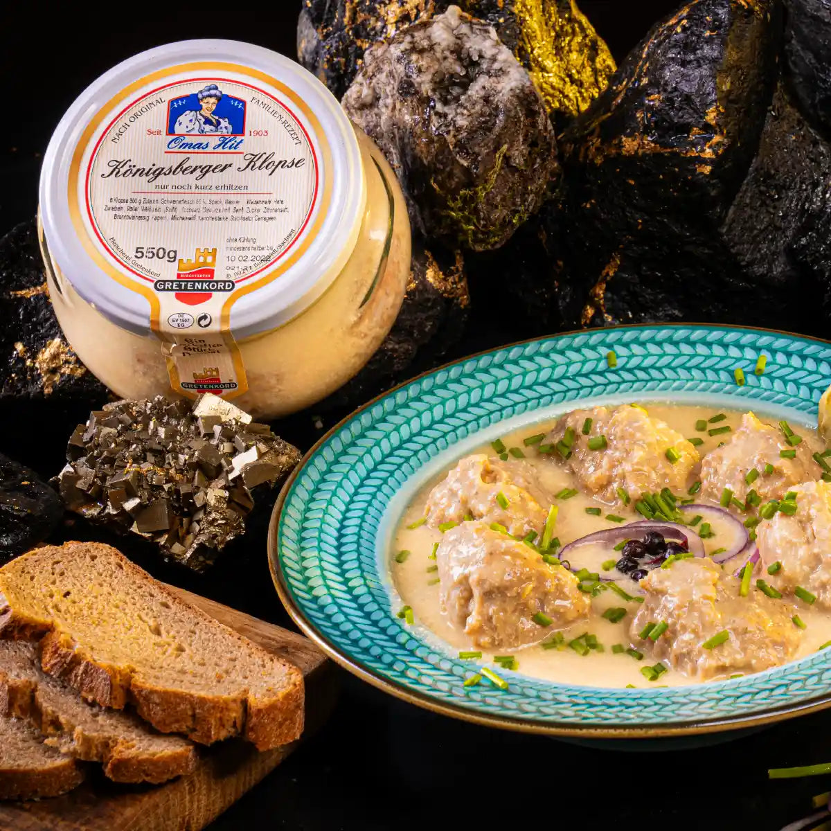 Königsberger Klopse im Glas angerichtet auf Teller neben Darm