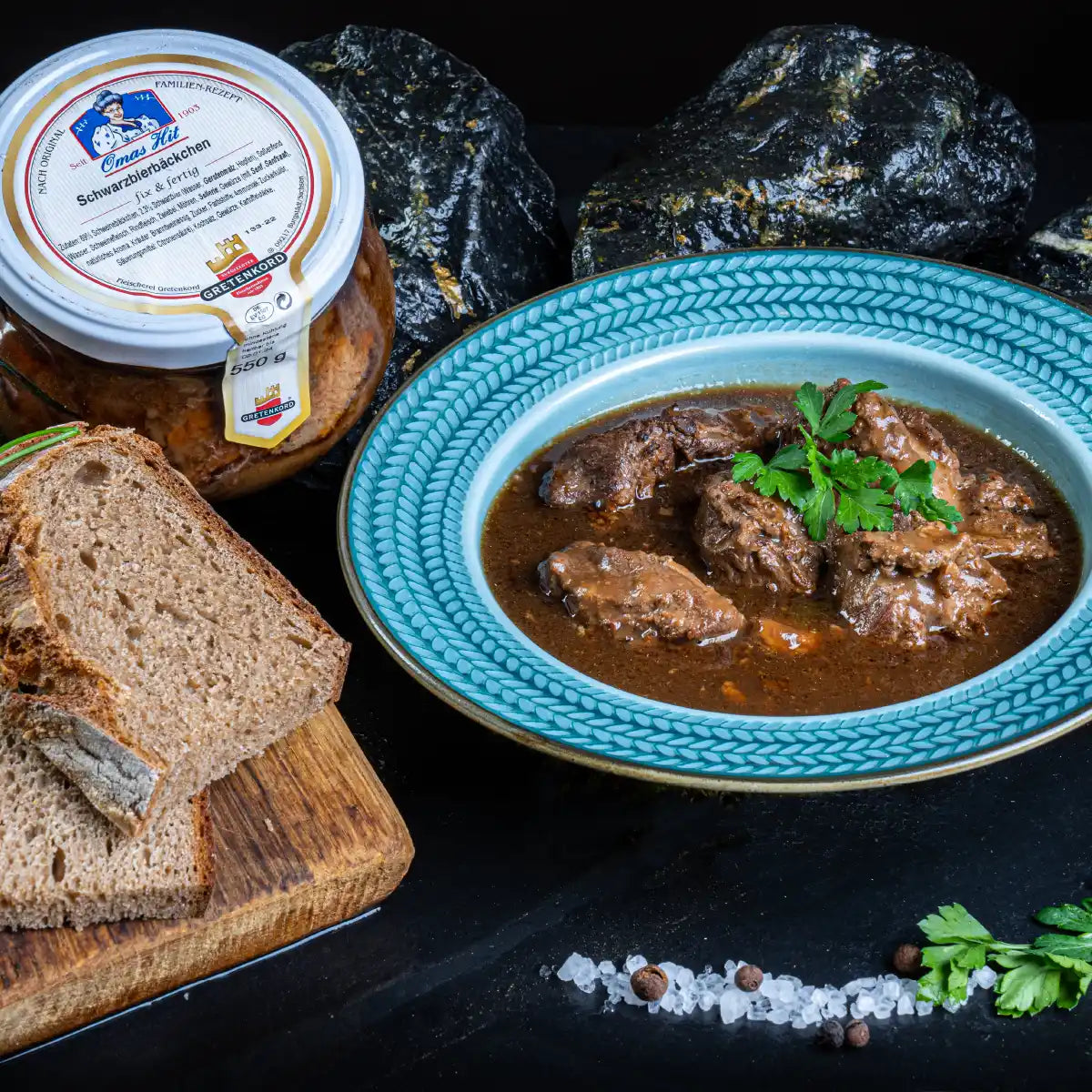 Schwarzbierbäckchen angerichet auf Teller neben Glas