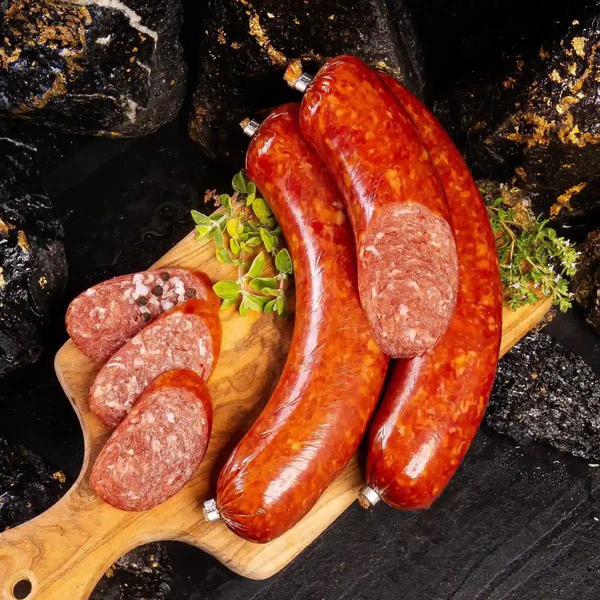 Drei Stangen Braunschweiger davon eine angeschnitten und daneben einige aufgeschnittene Scheiben