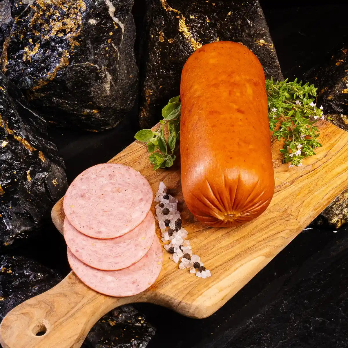 Eine komplette Burgstädter Jagdwurst und daneben aufgeschnitten einige Scheiben auf einem hellen Holzbrett