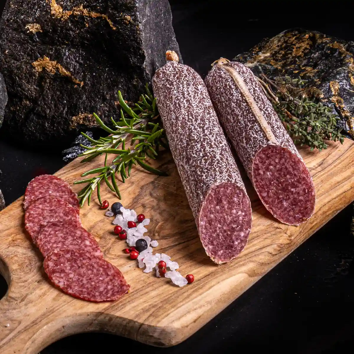 Zwei angeschnittene Stangen Edelsalami und daneben einige aufgeschnittene Scheiben