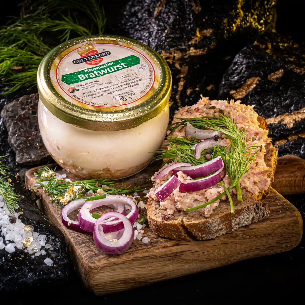 Ein Glas mit Hausmacher Bratwurst und daneben eine Scheibe Brot mit Aufstrich