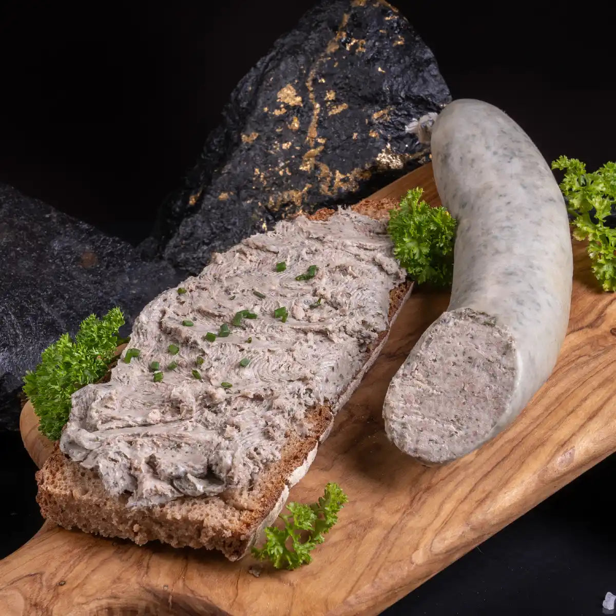 Eine aufgeschnittene frische Leberwurst und daneben eine Brotscheibe mit aufgestrichener Leberwurst