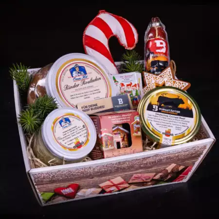 Geschenkbox aus Karton festlich geschmückt und mit Gläsern mit Hubertusschmalz, Rinder Rouladen und Deutschen Corned Beef. Rindersalami als Stück und in Zuckerstangen-Form.