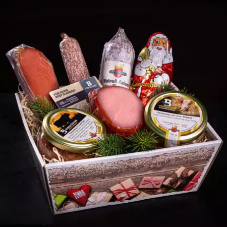 Geschenkbox im weihnachtlichen Design mit Schokoladenweihnachtsmann, Salamis, Lachsschinken und Produkten im Glas