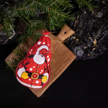 Salami in Form eines Weihnachtsmannes auf einem Holzbrett in festlichem Ambiente mit Tannenzweigen