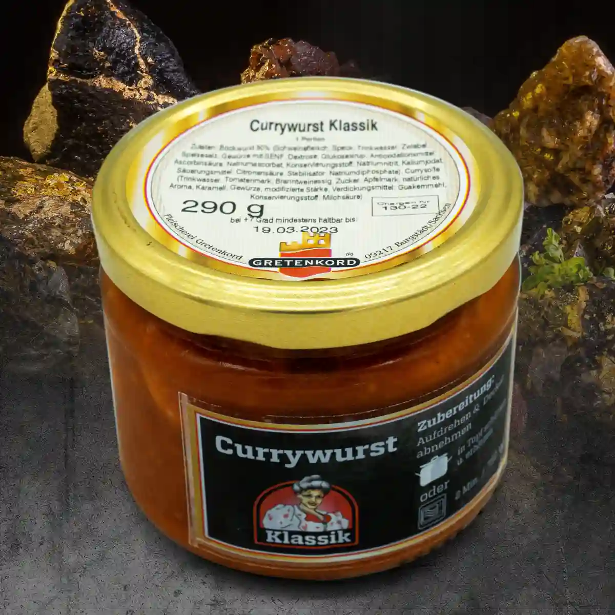 Ein Glas mit Currywurst Klassik vor einem Hintergrund aus Steinen